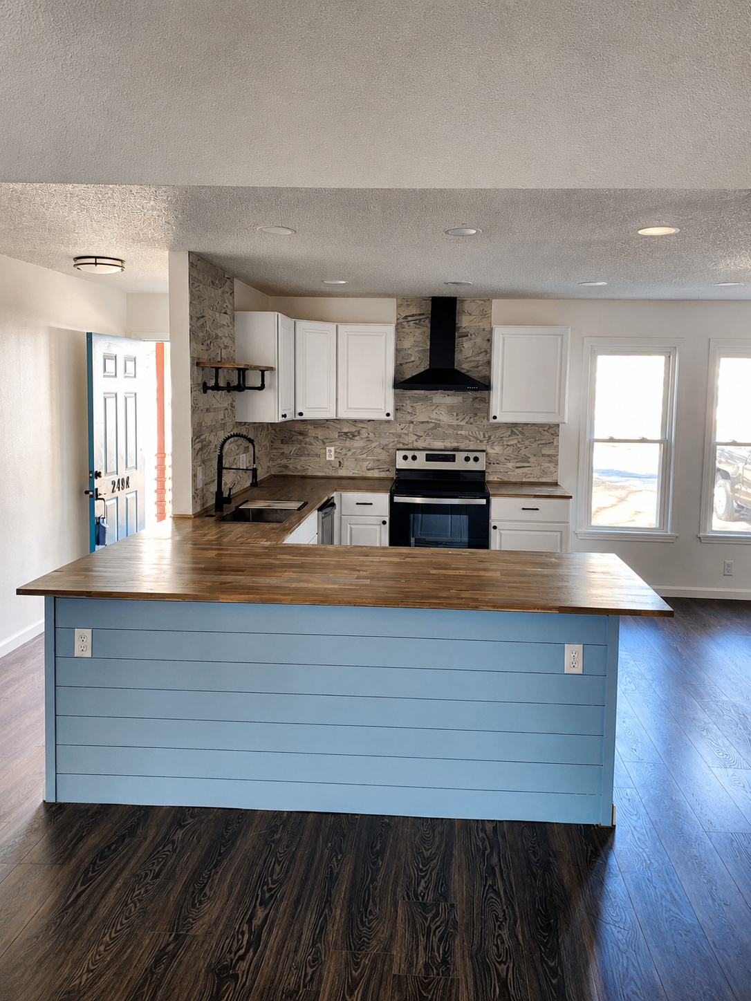 Kitchen renovation with white cabinetry, butcher block counters, and custom blue shiplap island