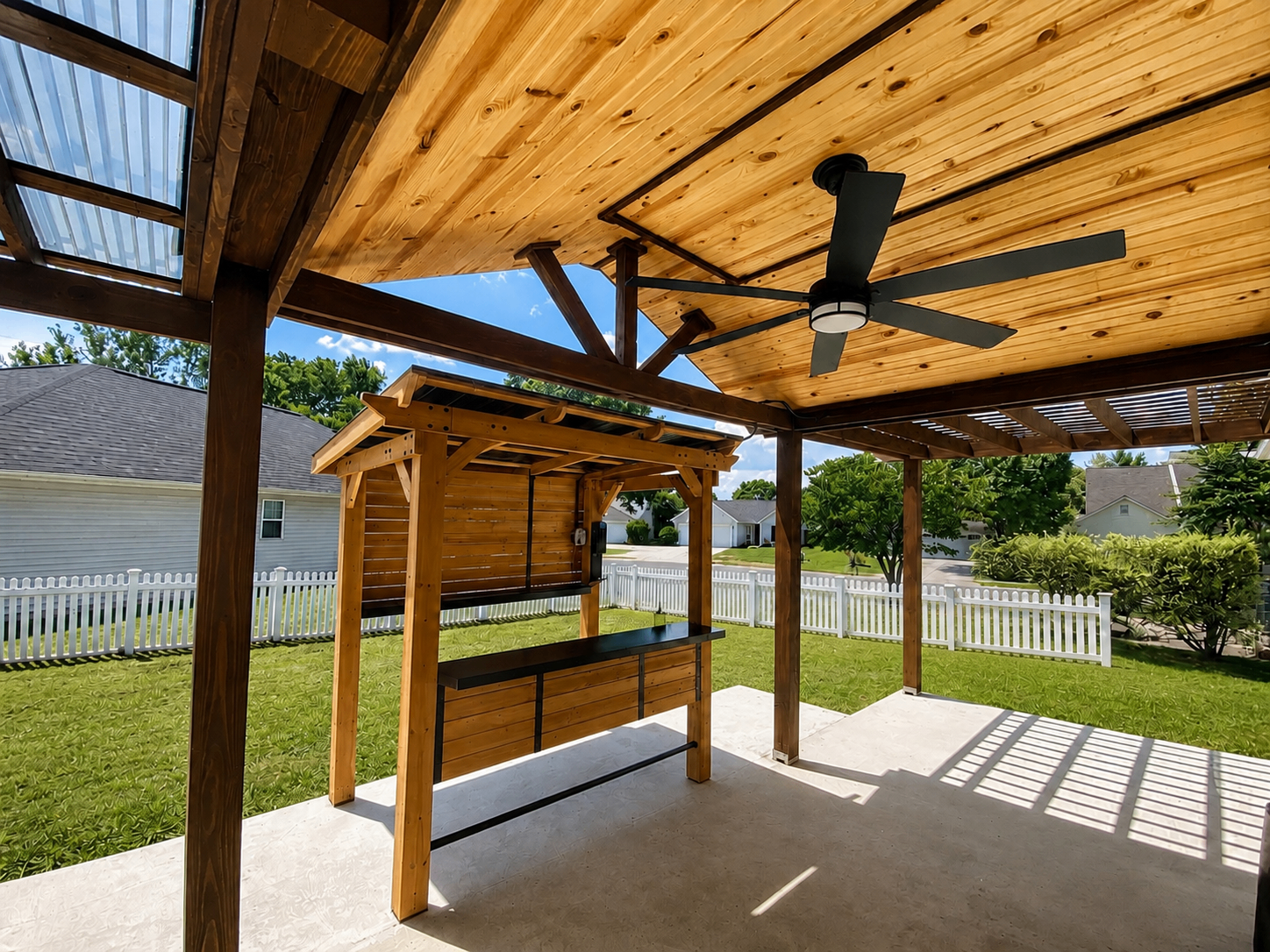 Under-pergola view with stained cedar ceiling, black ceiling fan, and outdoor grill station