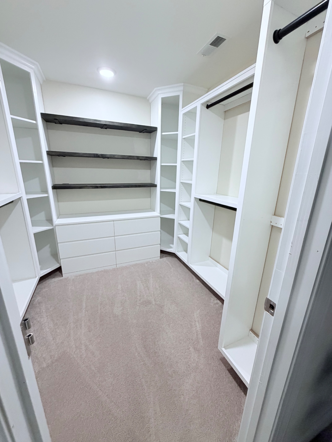 Custom walk-in closet with floating walnut shelves, drawer bank, and hanging systems