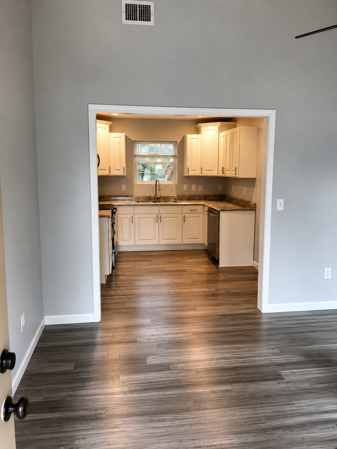 Cream kitchen viewed through a custom archway with warm wood-look flooring