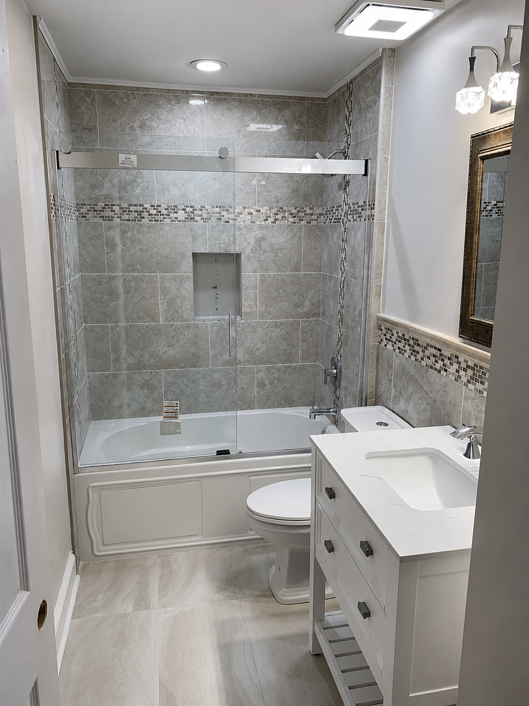 Bathroom remodel with marble-look tile tub surround, glass mosaic accent, and white quartz vanity