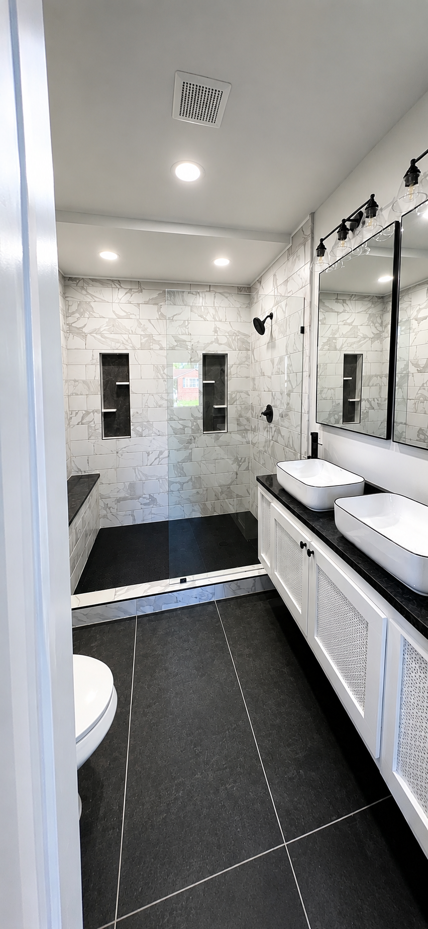 Modern black and white bathroom with marble shower, dual vessel sinks, and matte black fixtures
