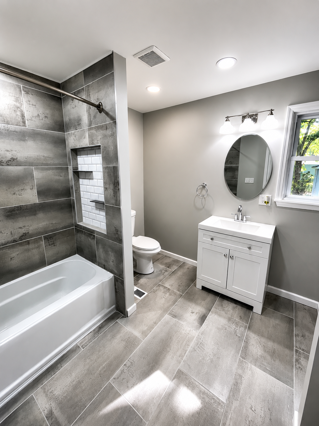 Full bathroom renovation with grey stone-look tile, custom niche, and modern vanity